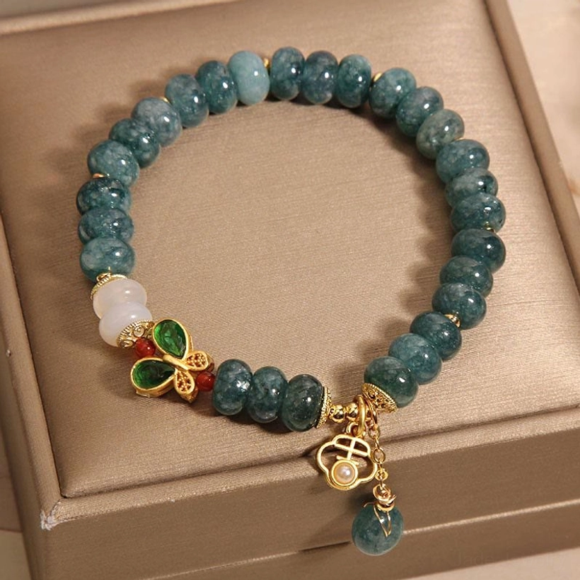 Minimalist white jade beaded bracelet with small dangle pendant on closed brown jewelry box, side view