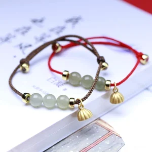 Two handmade jade bracelets in red and brown - natural jade beads with lotus pod charms on calligraphy paper