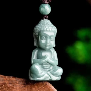 Close-up of polished light green jade Buddha amulet showing carved details and serene expression