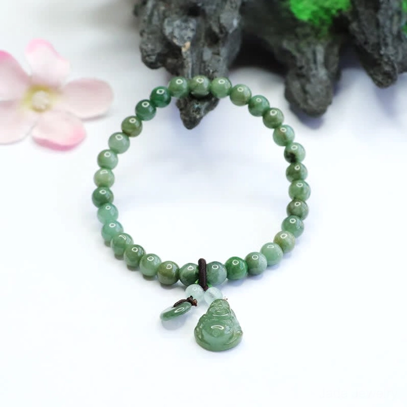 Hand-carved laughing Buddha jade bracelet with smooth green jade beads and small accent charm on rock and flower background