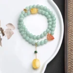 Handcrafted sterling silver jade butterfly bracelet with amber pendant on ceramic plate, showing double-loop design and tassel detail