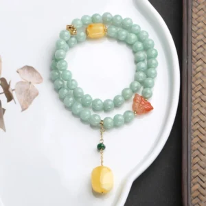 Handcrafted sterling silver jade butterfly bracelet with amber pendant on ceramic plate, showing double-loop design and tassel detail