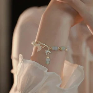 Adjustable jade butterfly bracelet front view on wrist with soft indoor lighting, featuring delicate gold chain accents and dangling jade pendant