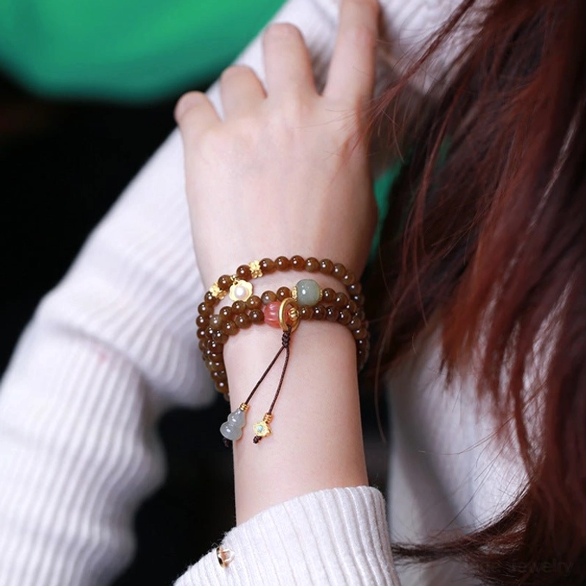 Jade butterfly gourd bracelet on wrist back view showing natural jade beads, gold decorative elements, and gourd charm tassel
