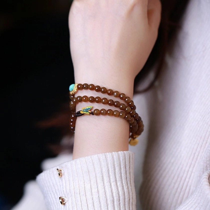 Jade butterfly gourd triple-wrap bracelet worn on wrist with white knitted sweater showing daily wear styling and side view