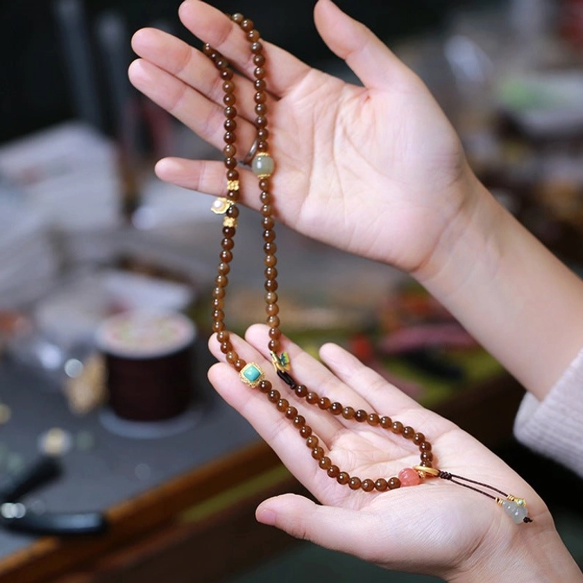 Jade butterfly gourd necklace and bracelet set held in hands showing versatile 2-in-1 styling with mixed natural beads and metal accents
