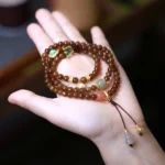 Premium jade butterfly gourd prosperity bracelet with natural jade beads, red agate, and gold-accented gourd charm displayed on palm