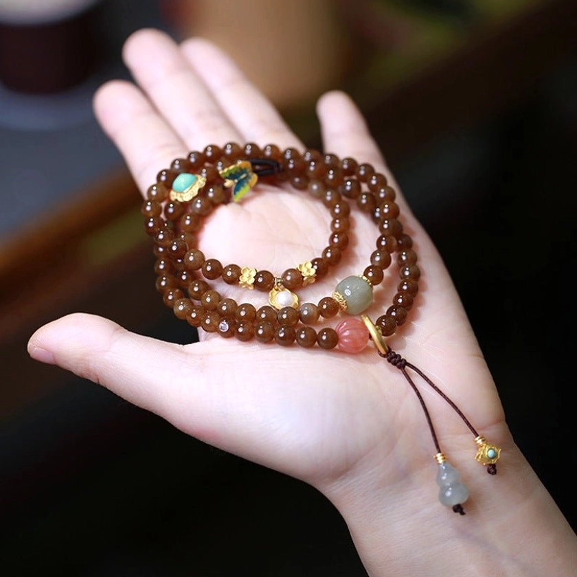 Premium jade butterfly gourd prosperity bracelet with natural jade beads, red agate, and gold-accented gourd charm displayed on palm