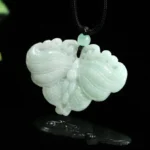 Hand-carved natural jade butterfly pendant necklace close-up on black reflective background showing intricate wing details