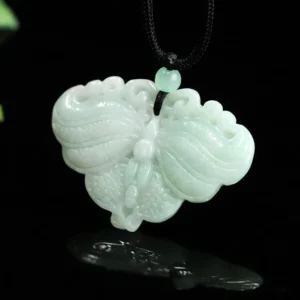 Hand-carved natural jade butterfly pendant necklace close-up on black reflective background showing intricate wing details