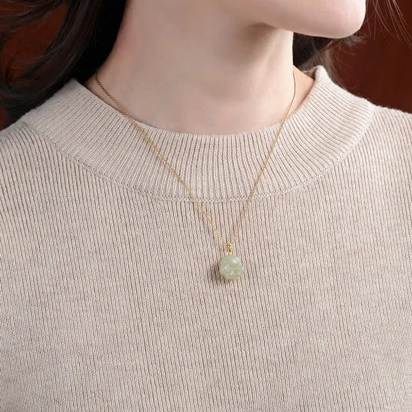 Hetian white jade cat paw necklace worn on neck with thin gold chain against beige knit sweater background