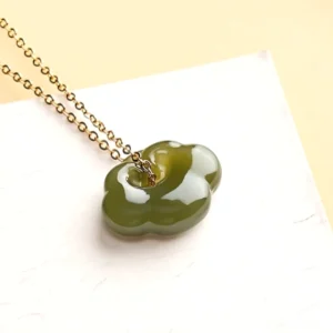 Close-up detail of handcrafted jade cloud lock pendant showing intricate carved auspicious cloud symbol and polished smooth nephrite surface