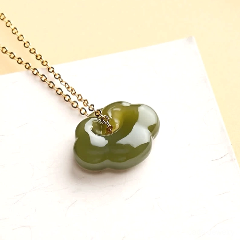 Close-up detail of handcrafted jade cloud lock pendant showing intricate carved auspicious cloud symbol and polished smooth nephrite surface