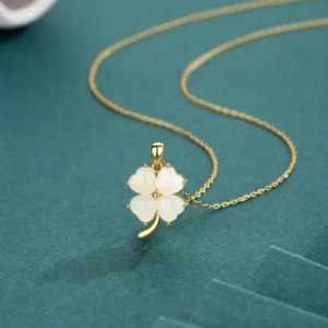 Four leaf clover jade necklace pendant with polished white jade charm and curved gold chain - side angle view