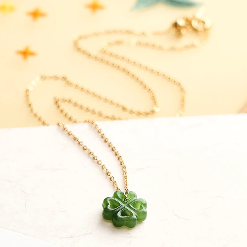 Jade four-leaf-clover luck pendant necklace overhead flat lay with gold chain displayed