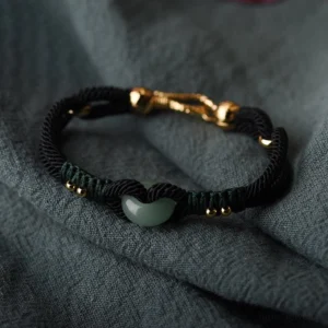 Close-up detail of Tibetan jade couple bracelet showing heart-shaped jade pendant with gold beads and woven knot design