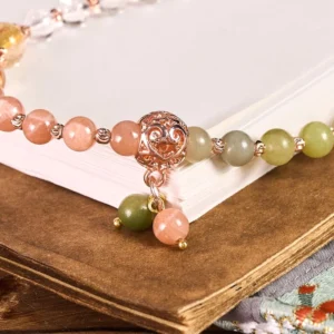 Close-up detail of carved rose gold connector and mixed gemstone beads on vintage book display