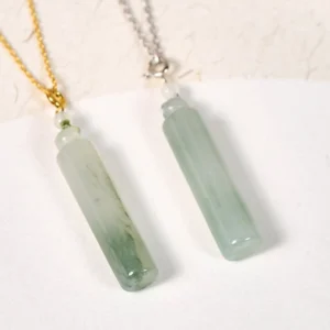 Two cylindrical green jade pendant necklaces with gold and silver chains displayed on white background, showing natural jade veining and color variations