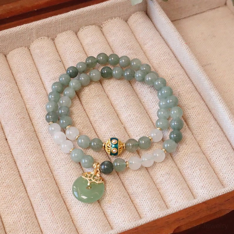 Double strand jade bracelet with peace buckle charm showing mixed jade beads, gold metal details, and jade peace buckle on jewelry display tray