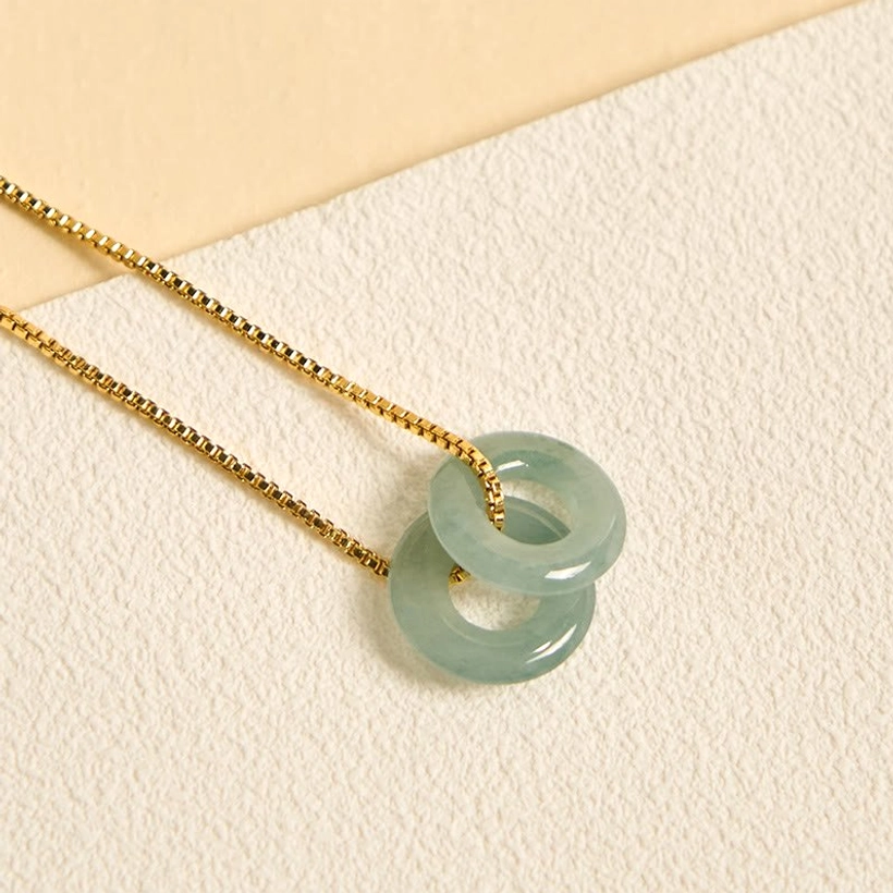 Double stacked jade peace buckle pendant with delicate gold chain, close-up side view on neutral background