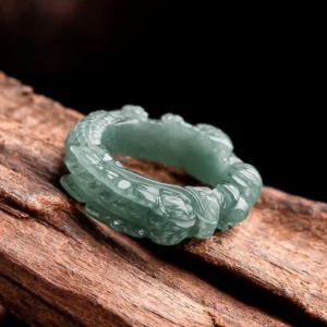 Jade dragon ring oblique top view on polished wood background, displaying raised dragon pattern and jade texture