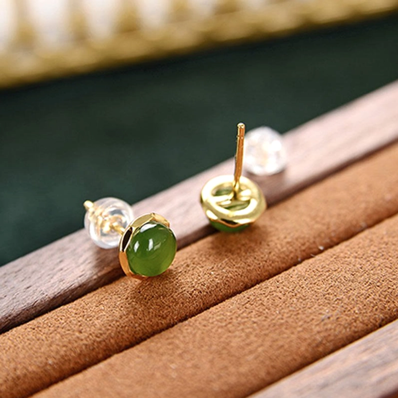 Single jade stud earring component with gold metal backing and acrylic ear back on velvet display, showing detailed stud construction
