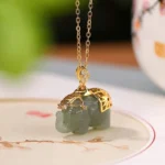 Natural green jade elephant pendant with gold-plated silver saddle, front view showcasing intricate hand-carved details and authentic color