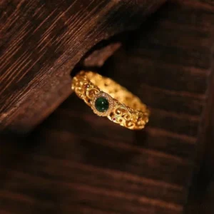 Side oblique angle view of cyan jade jade ring displaying delicate filigree scrollwork pattern with dark green central jade stone