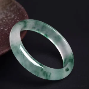 Natural jade floating flower bangle bracelet with green and white marbled pattern, high-angle side view