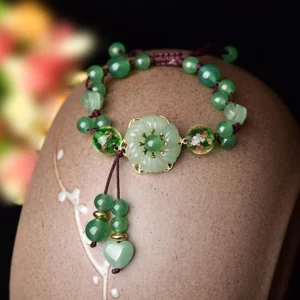 Close-up detail of green jade and aventurine beads on ceramic stand showing stone texture and craftsmanship