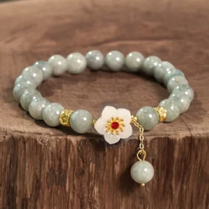 Jade beaded bracelet with gold metal spacers and round matte jade beads, flat lay on wooden surface