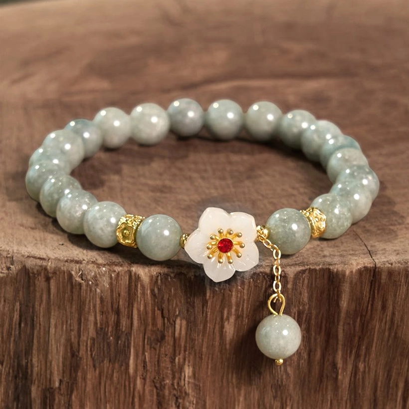 Jade beaded bracelet with gold metal spacers and round matte jade beads, flat lay on wooden surface