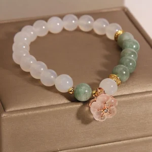 Overhead view of jade flower charm bracelet showing alternating white agate and green jade beads with pink floral pendant
