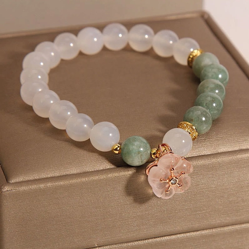 Overhead view of jade flower charm bracelet showing alternating white agate and green jade beads with pink floral pendant