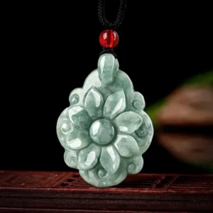 Side angle view of natural jade flower pendant revealing detailed embossed carving work, layered petals, and red accent bead, showcasing artisan craftsmanship