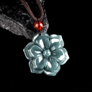 Three-quarter view of jade flower pendant showing carved details and polished finish with brown woven cord and red glass bead