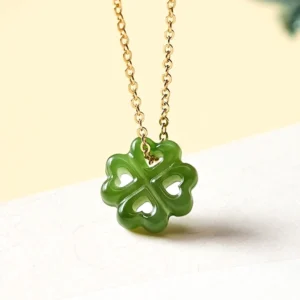 Hand-carved Hetian jade four leaf clover pendant necklace in green with gold-toned chain, front view close-up