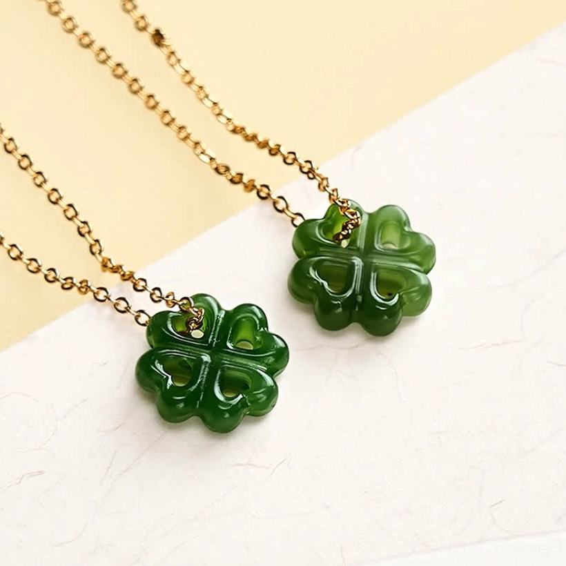 Two identical hand-carved green jade four-leaf clover pendants with matching gold chains