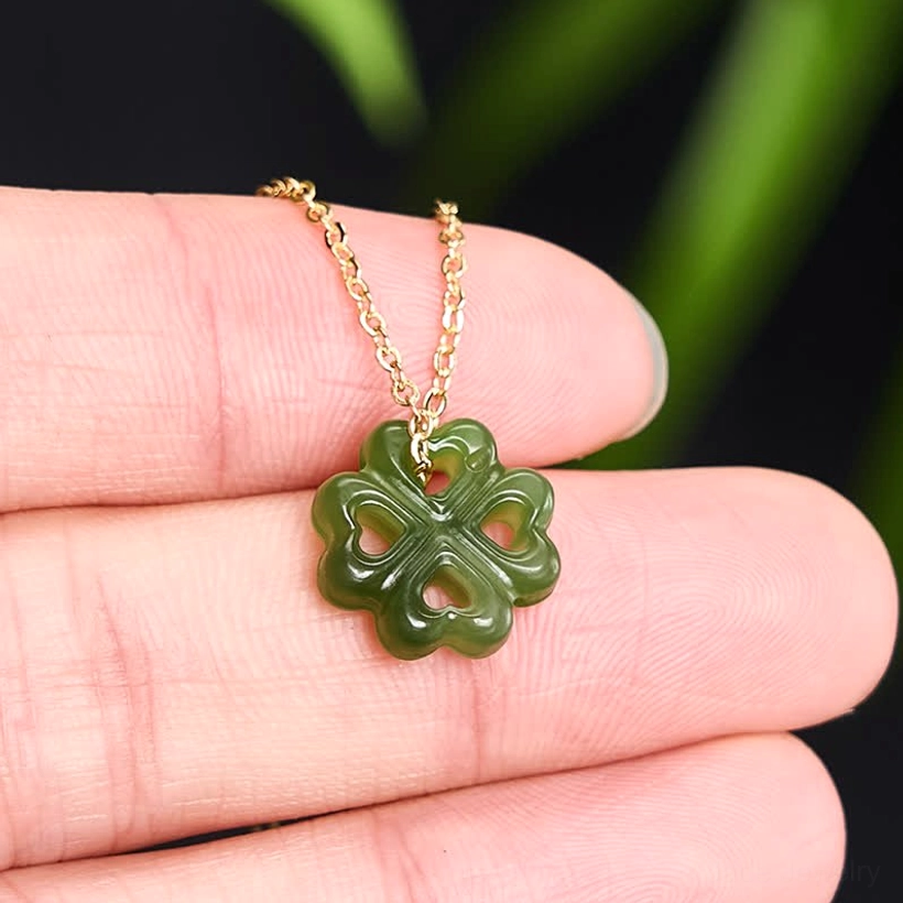 Hand-held four-leaf clover jade pendant showing actual size and delicate chain detail