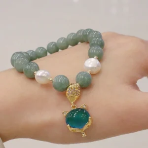 Worn jade fox charm bracelet on hand, close-up view showcasing green jade beads, white pearls, and blue color-changing fox pendant