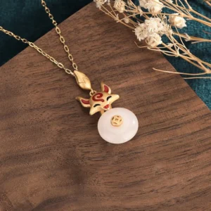 Left side view of white jade fox pendant showing matte gold fox head detail and jade donut on wooden background
