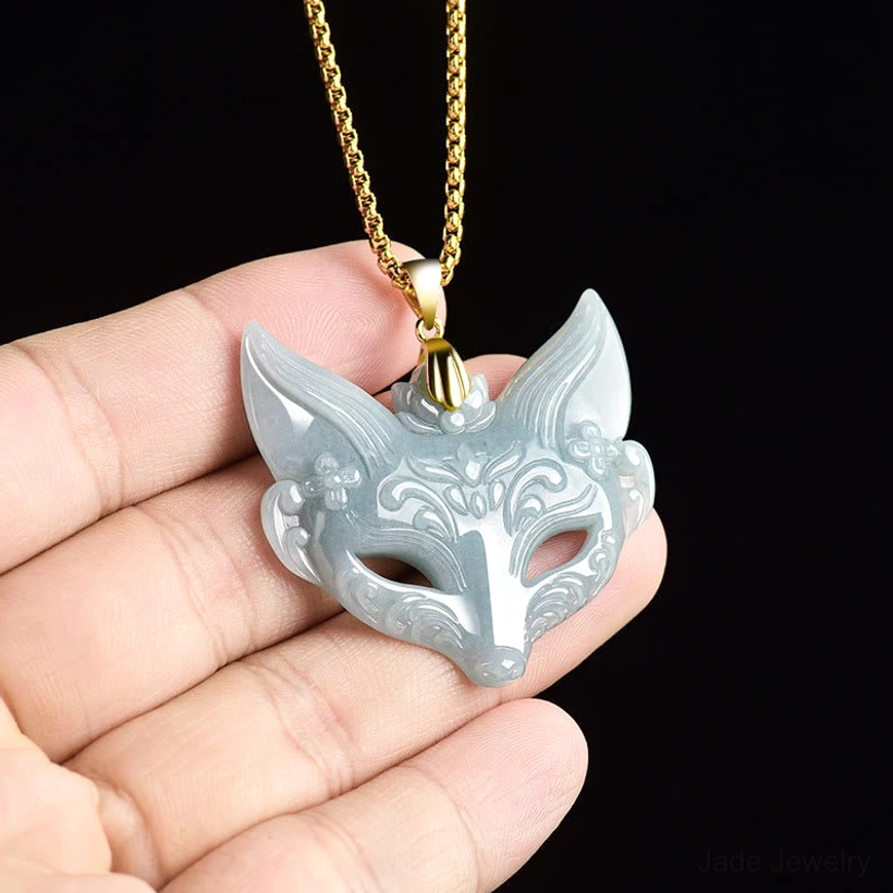 Hand-held fox mask jade pendant with carved floral details, showing natural jade color and polished titanium steel chain in first-person perspective