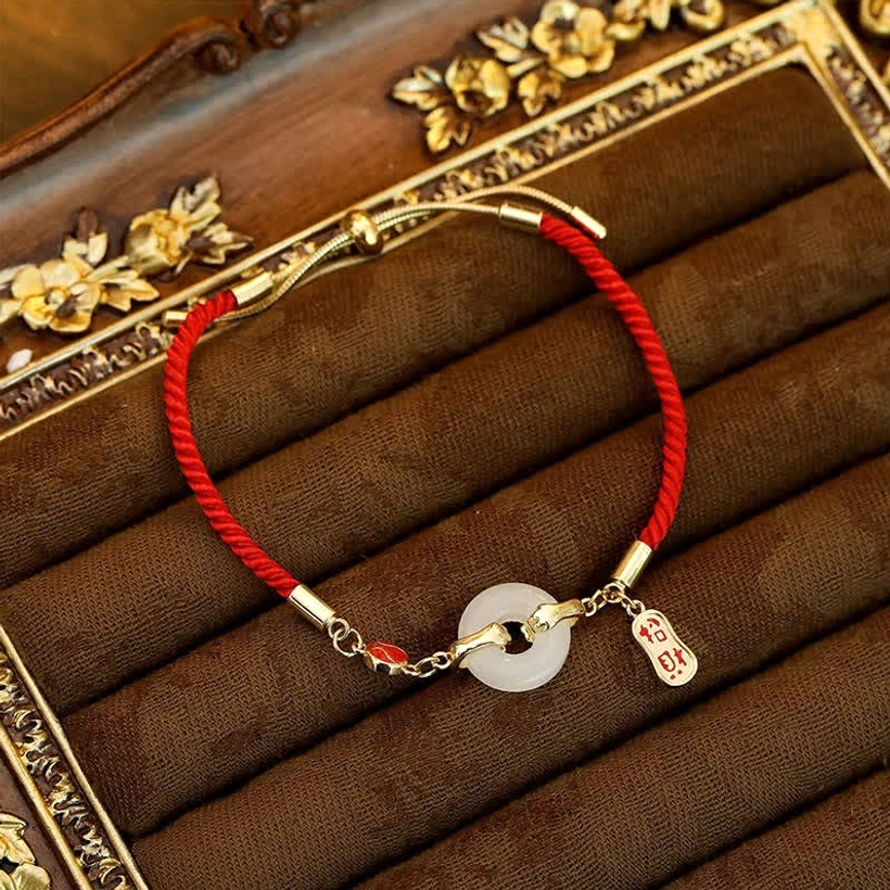 Fu character jade blessing bracelet with adjustable clasp shown on decorative velvet tray, left-side perspective