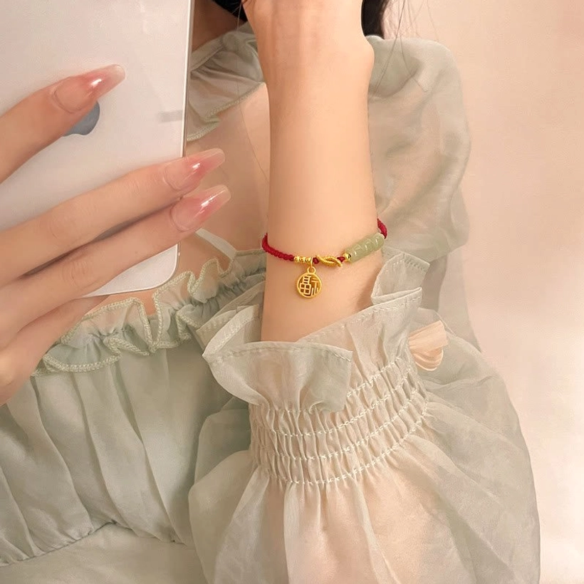Handcrafted red rope jade Fu bracelet - detailed view of natural jade stone beads and gold Fu character pendant charm