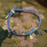 Natural jade beads navy blue braided bracelet with gold gourd pendant Fu character symbol on floral fabric background