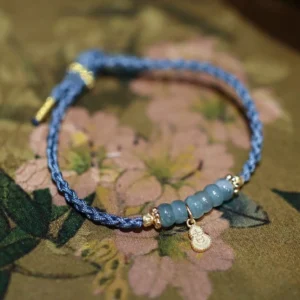 Natural jade beads navy blue braided bracelet with gold gourd pendant Fu character symbol on floral fabric background