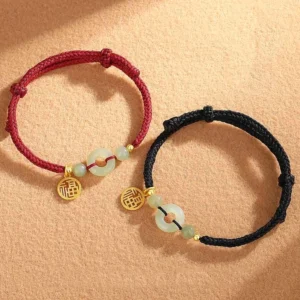 Two matching jade peace buckle bracelets with red and black braided cords, light green jade beads and gold fu character charms