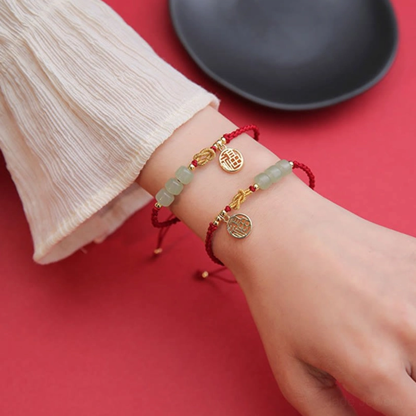 Handcrafted jade Fu prosperity bracelet - full view showing braided red cord, light green jade beads, and gold Fu character charm
