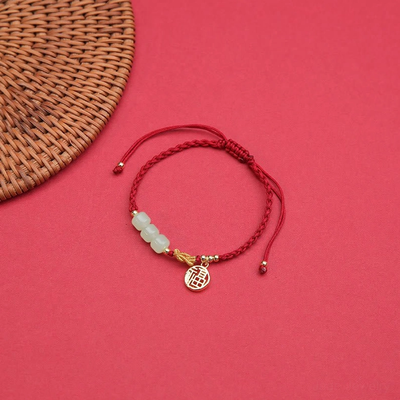 Single jade Fu character bracelet with red braided cord and gold charm on solid red background - adjustable wrist wear