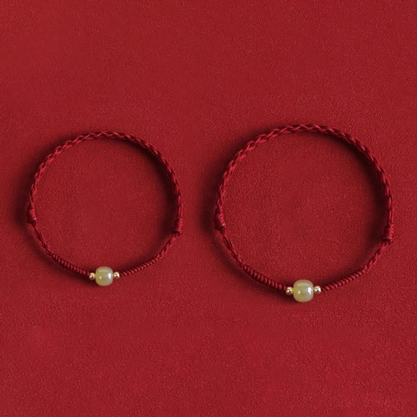Two matching Hetian jade gold bead protection bracelets red background
